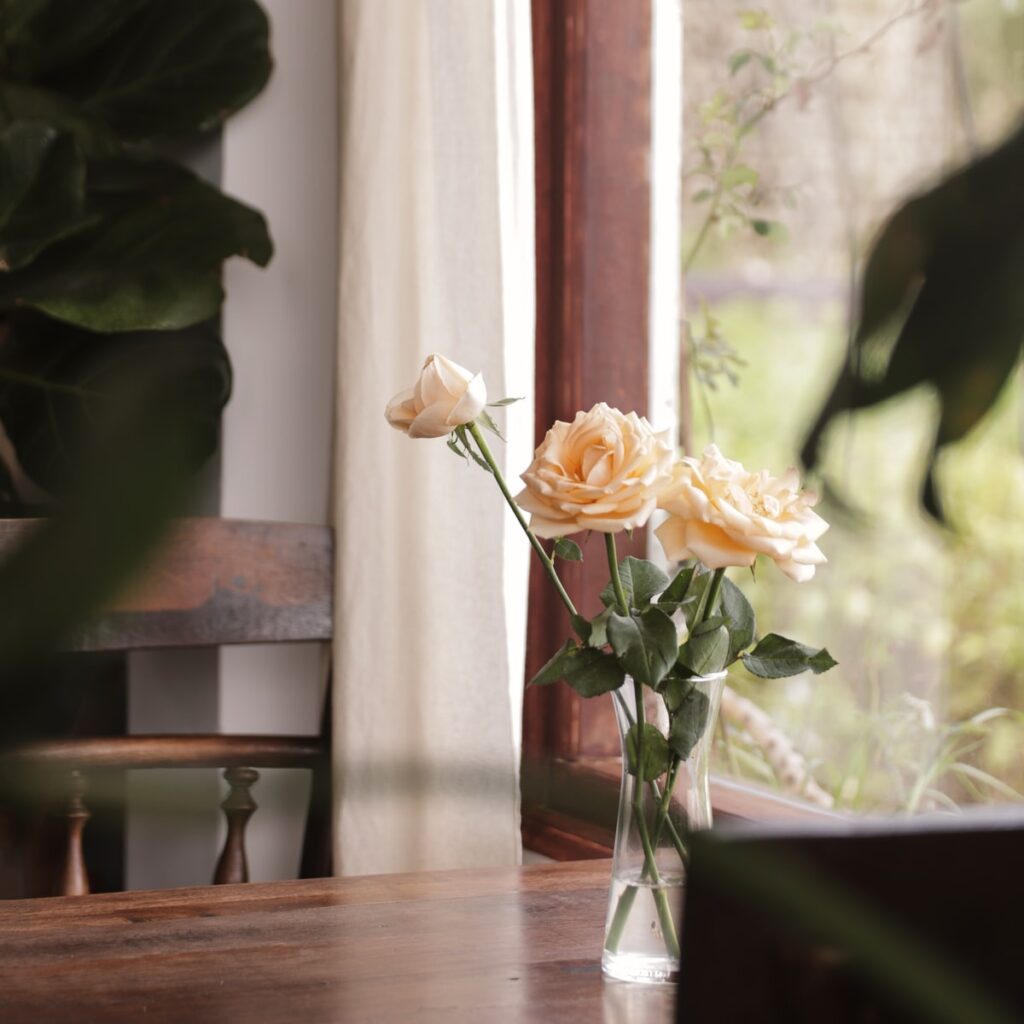 white roses in clear glass vase on brown wooden table